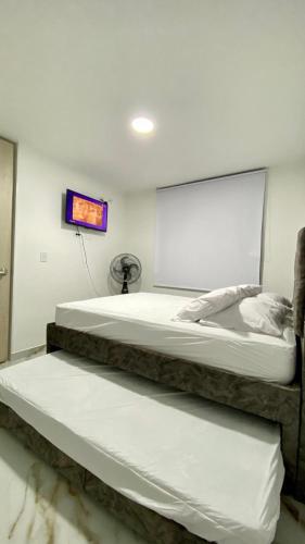 two beds in a room with a tv on the wall at Apartamento Mirador la Estancia in Melgar