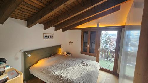 um quarto com uma cama e uma janela grande em Half chalet 2 min from ski bus em Laax
