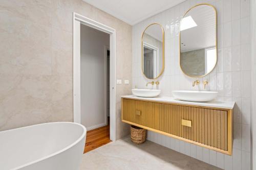 a bathroom with two sinks and two mirrors at Dovestones by the Sea Inverloch in Inverloch