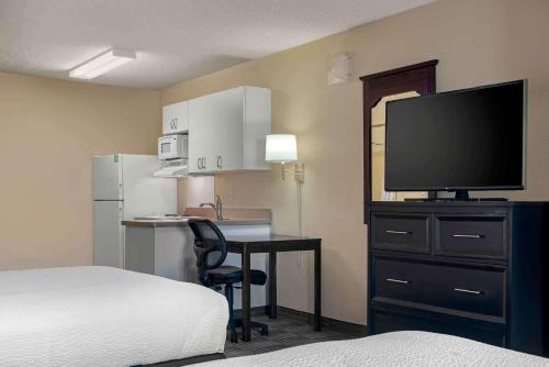une chambre d'hôtel avec un lit et un bureau avec une télévision dans l'établissement Extended Stay America Suites - Sacramento - Arden Way, à Sacramento