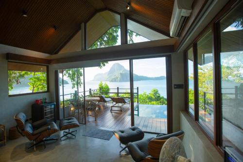 a living room with large windows and a view of a mountain at Morgan Villas in El Nido