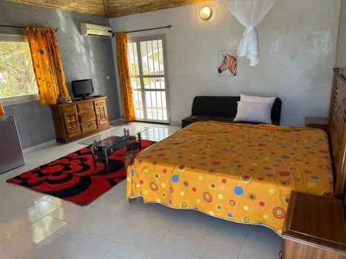 a bedroom with a large bed and a tv at Villa Paco in Mbour