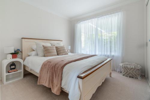 a white bedroom with a large bed and a window at 8 min to beach, Sleep 12 and Pets in Port Macquarie