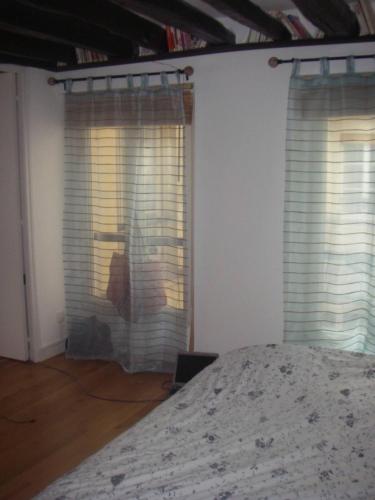 - une chambre avec deux fenêtres avec des stores et un lit dans l'établissement Appartement dans le Marais avec terrasse, à Paris