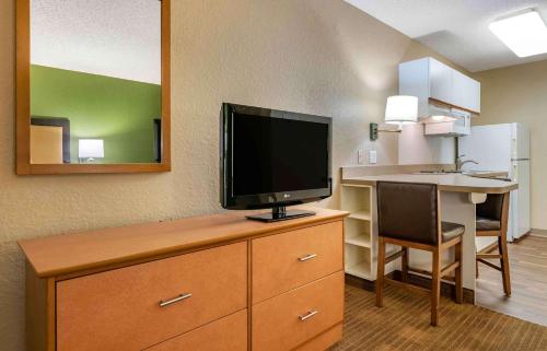 a hotel room with a television on a dresser with a desk at Extended Stay America Suites - Orlando - Altamonte Springs in Orlando