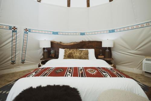a bedroom with a large white bed with a headboard at Oso Tipi at El Mistico Ranch in Nogal