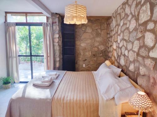a bedroom with a bed and a stone wall at Refugio del Valle in La Falda