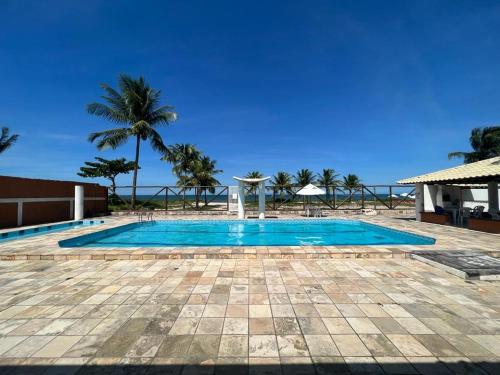 une piscine avec un palmier en arrière-plan dans l'établissement Apartamento frente ao mar na praia do guaibim., à Guaibim
