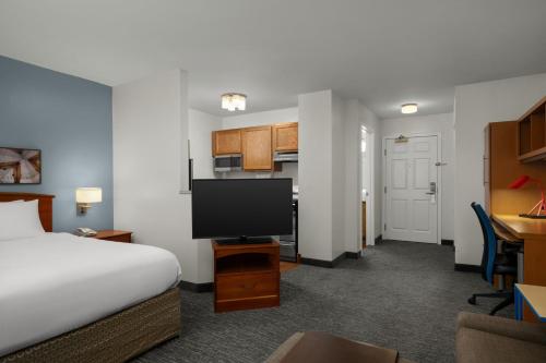a hotel room with a bed and a flat screen tv at TownePlace Suites Salt Lake City Layton in Layton