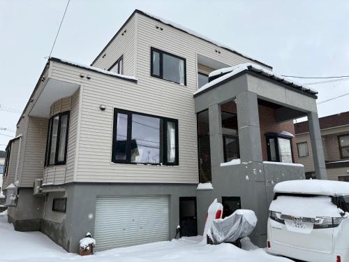 a snow covered house with a car parked in front of it at ShareHouse新琴似,駐車無料,麻生駅バス直通 in Sapporo