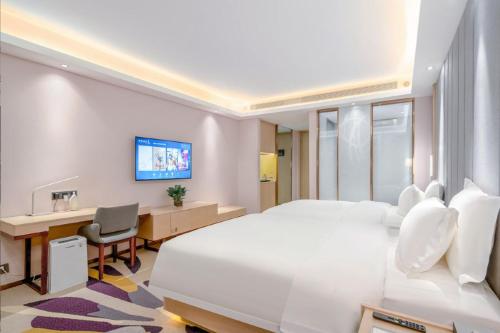 a hotel room with a large white bed and a desk at Lavande Hotel Xi'an Xianyang International Airport Outlet in Xianyang