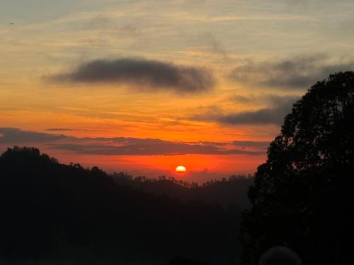 a sunset in the mountains with the sun in the sky at Saris Sweet Dream Villa in Kubupenlokan
