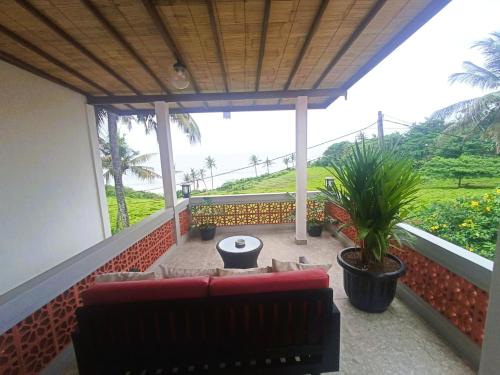 a balcony with a couch and a view of a hill at Pondok Pisces Bungalows Balian Beach in Selemadeg