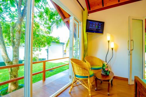 a room with a balcony with chairs and a table at Kurumba Luxury Cabin in Ahangama