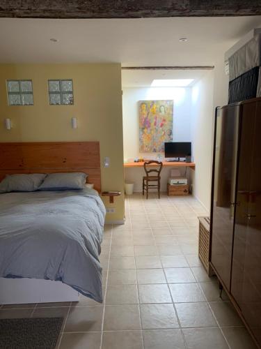 a bedroom with a bed and a desk and a refrigerator at Quiet street in old Mèze - terrace, 250m to beach in Mèze