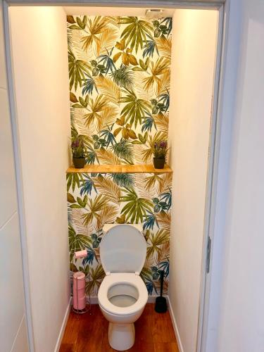 - une salle de bains avec toilettes dans une chambre avec papier peint en palmier dans l'établissement Les Perles d'Opale - L'Eclat des Flots - Duplex, à Boulogne-sur-Mer