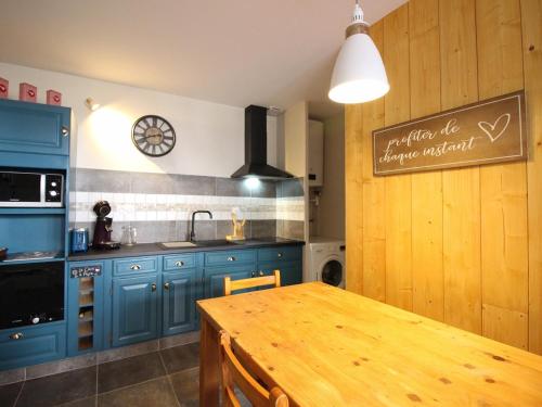 une cuisine avec des placards bleus et une table en bois dans l'établissement Charmant T2 au Mont Dore, 4 pers, Animaux admis, Équipements modernes - FR-1-608-275, à Mont-Dore
