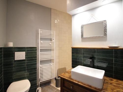 La salle de bains est pourvue d'un lavabo blanc et de carrelage vert. dans l'établissement Charmant T2 au Mont Dore, 4 pers, Animaux admis, Équipements modernes - FR-1-608-275, à Mont-Dore