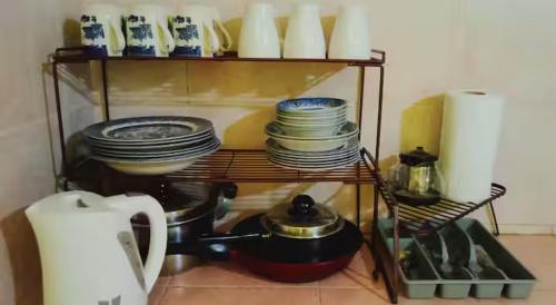 a shelf with plates and other dishes on it at Bagas Zakariah Orchard Lodge in Gopeng