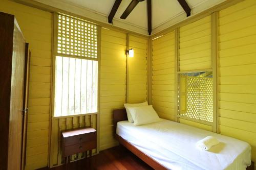 a small room with a bed and two windows at Bagas Zakariah Orchard Lodge in Gopeng