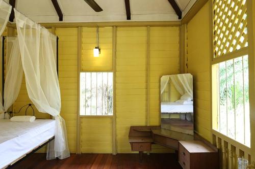 a yellow room with two beds and two windows at Bagas Zakariah Orchard Lodge in Gopeng