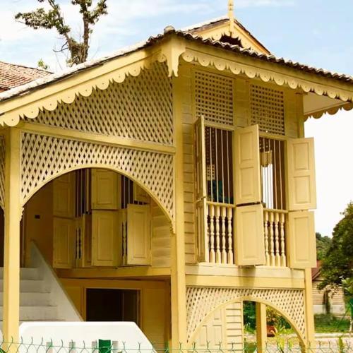 a large yellow building with a porch and stairs at Bagas Zakariah Orchard Lodge in Gopeng