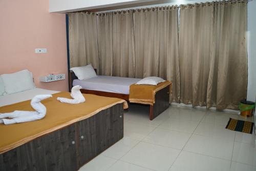 two beds in a room with two swans on them at ALAYA ROOMS in Tiruchchirāppalli