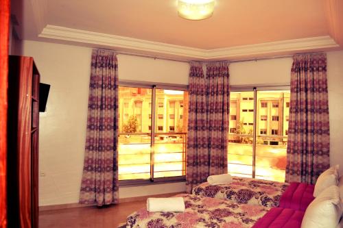 a bedroom with a bed and a large window at Hotel La Place in El Jadida