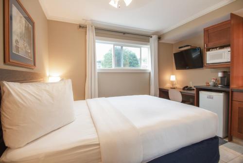 a bedroom with a large white bed and a window at Buccaneer Inn in Nanaimo