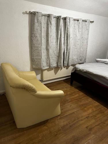 a bedroom with a chair and a bed and curtains at AT Apex House S in Dagenham