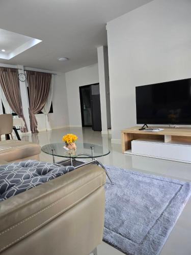 a living room with a couch and a glass table at PS homehug2 in Ban Non Sa-at