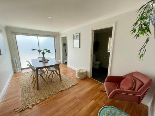 a living room with a table and a chair at The Sweet Grapevine Cottage in Cessnock