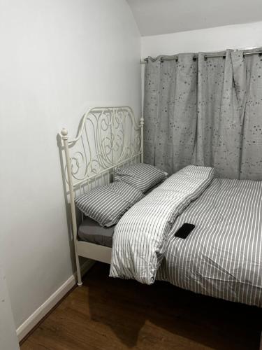 a bedroom with a bed with a curtain and a bedskirts at AT Apex House S in Dagenham