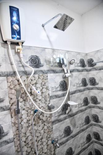 a shower in a bathroom with a stone wall at Bliss Inn in Udawalawe