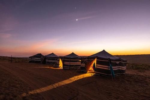 a group of tents in the desert at sunset at SandGlass Camp in Bidiyah