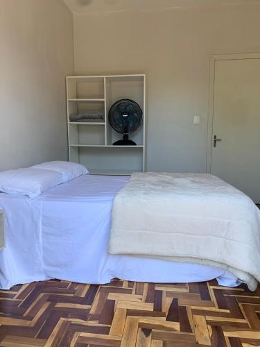 a bedroom with a bed and a clock on a shelf at Dodora Pousada Hostel in Bento Gonçalves