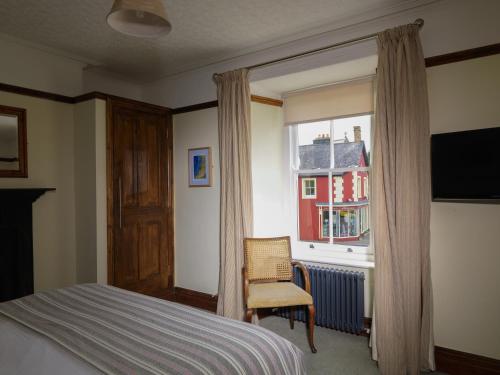 ein Schlafzimmer mit einem Bett, einem Fenster und einem Stuhl in der Unterkunft Y Talbot in Tregaron