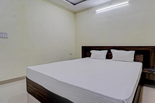 a bedroom with a large bed with white sheets at Super HOTEL O MIDWAY TREAT DHAR in Dhār