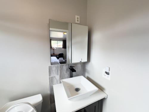 a white bathroom with a sink and a mirror at Private Home - #RedwoodSkyWalkRetreat - 5BD, Pro Pool Table, BBQ, Foosball, Darts, Fireplace, Movie Projector, Stereo, Cotton Bedding in Eureka