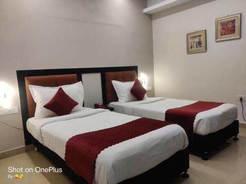 a hotel room with two beds with red and white sheets at Hotel Delphi Grand Hyderabad - Hi-Tech City, Perfect for Business & Comfort in Hyderabad