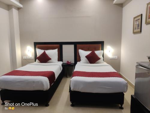 two beds in a hotel room with red and white pillows at Hotel Delphi Grand Hyderabad - Hi-Tech City, Perfect for Business & Comfort in Hyderabad