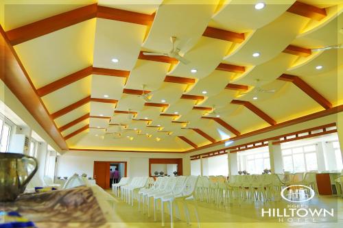 a banquet hall with white chairs and a ceiling at Kgees - Hill Town Hotel in Kattappana