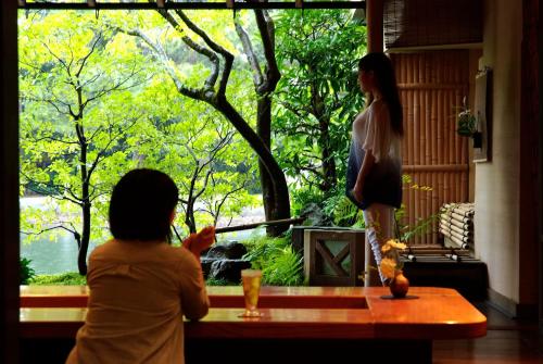 a woman standing at a table looking out of a window at Taikyourou in Miyazu