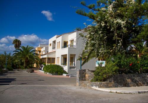 a large white building with trees and a street at Lycasti Maisonettes in Tavronitis