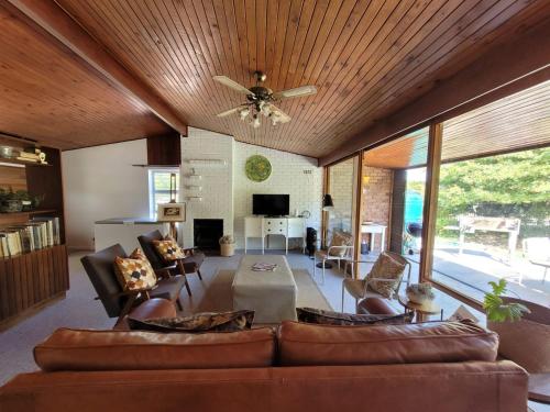 Una sala de estar con sofás y un ventilador de techo. en Mid Century Modern Gem near town, en Stellenbosch