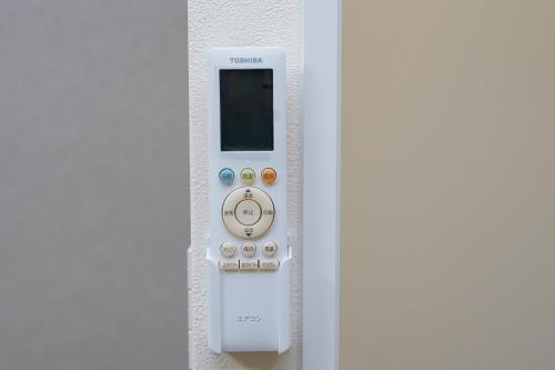 a white remote control attached to a wall at Osaka Nimi family house direct KIX airport in Osaka