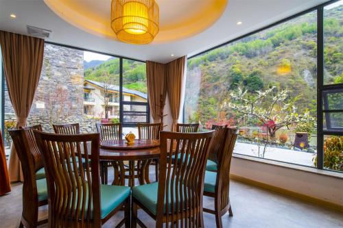 a dining room with a table and chairs and a large window at Summergarden Hotel in Wolongguan