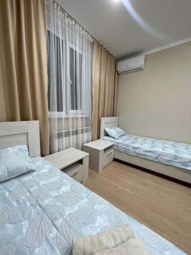 a small room with two beds and a window at Филиал Aport Hostel Alma-Ata на Муратбаева 195 in Almaty