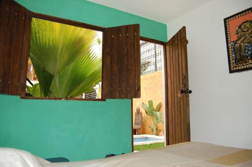 a bedroom with a bed and a window with a plant at La Choza Guesthouse in Santo Domingo