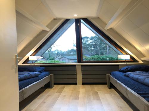 a large window in a room with two beds in front of it at Bungalow for 12 guests on holiday park Vosseven in Stramproy